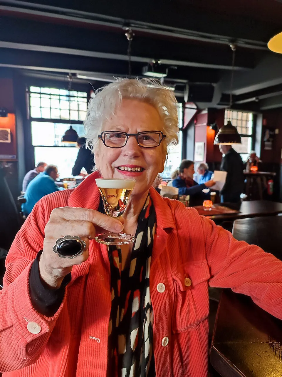Een bezoekster heft lachend het glas in het Oranje Bierhuis