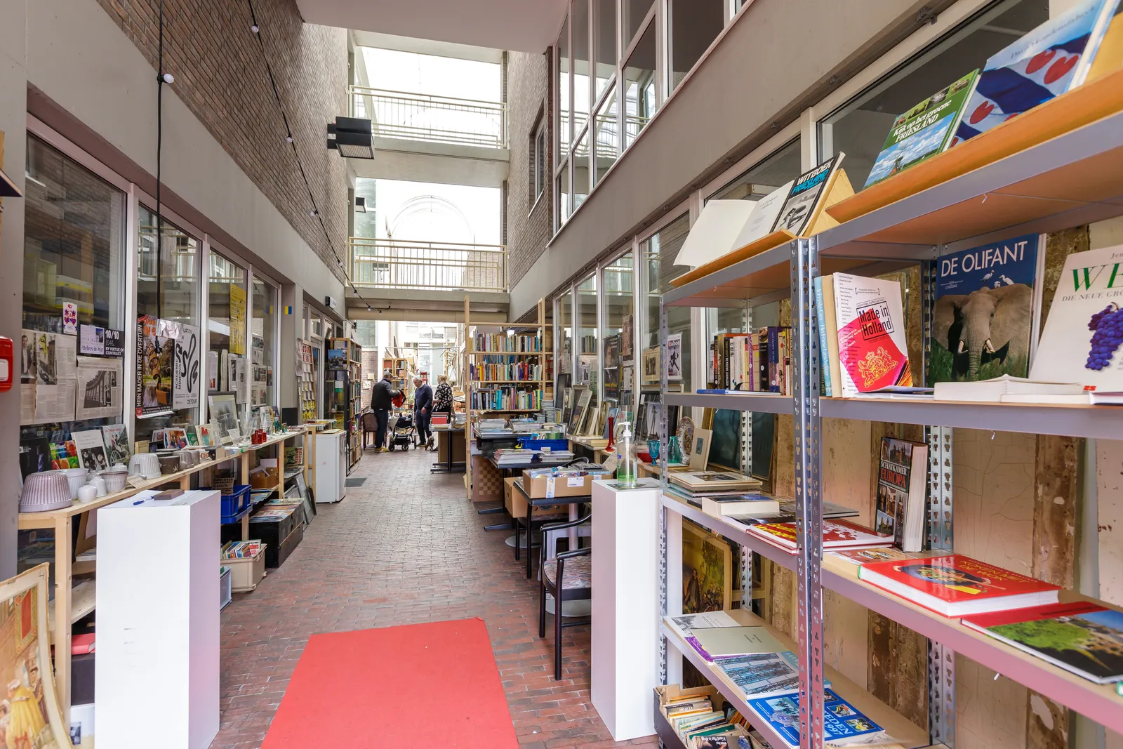 De rode loper door de passage, met boekenkasten en uitstallingen aan beide kanten onder het glazen dak
